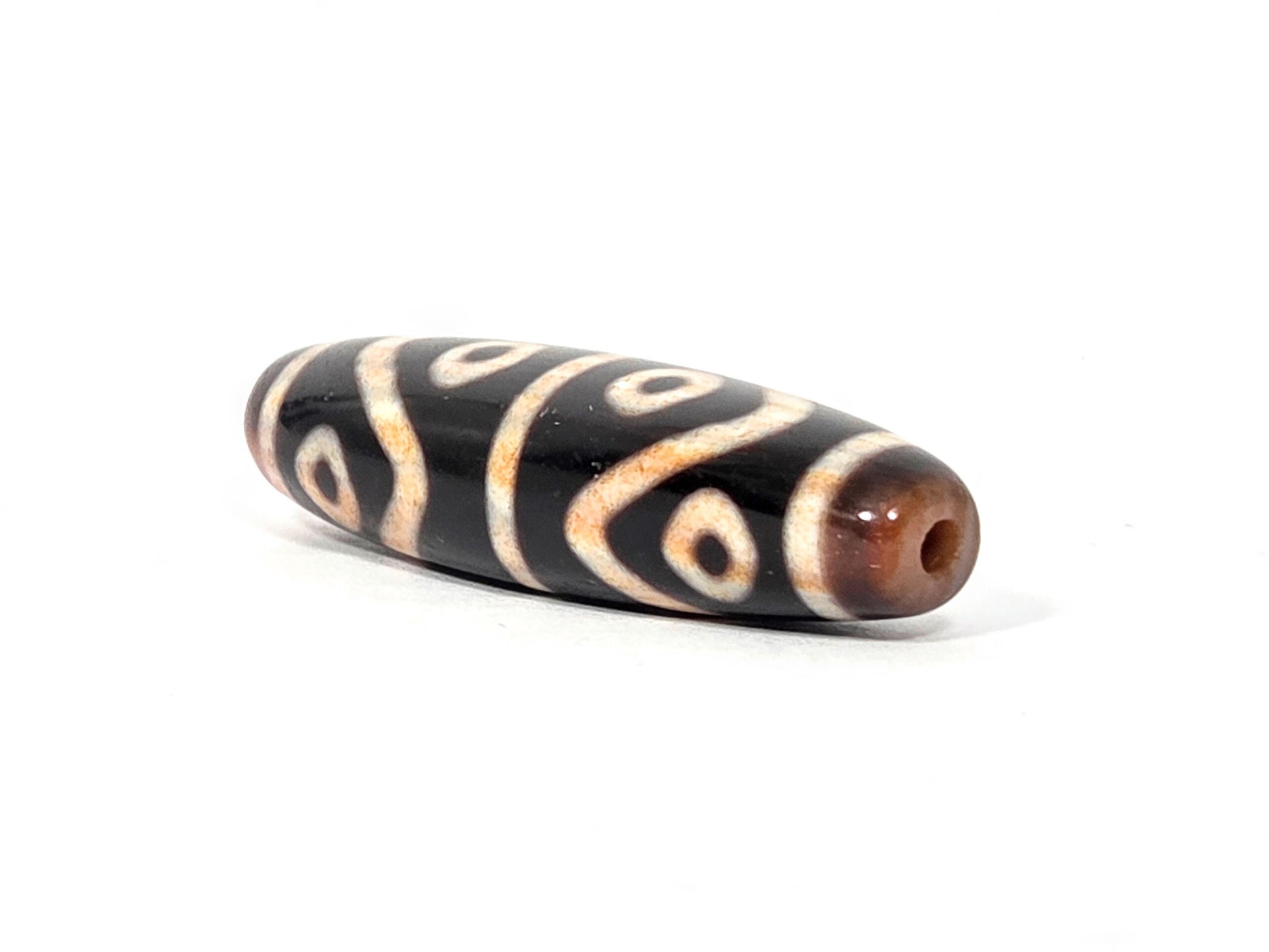 Second end of antique Eight Eye Tiger Tooth Dzi — drill hole, warm amber agate, eye circles wrapping end