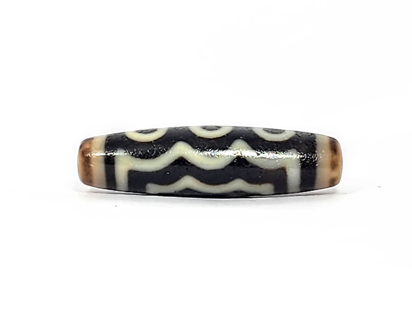 Face D of antique five eye dzi At-072625-5E, partial eye rings at top edge transitioning to two rows of cream wave lines below, pitch-black agate, unretouched