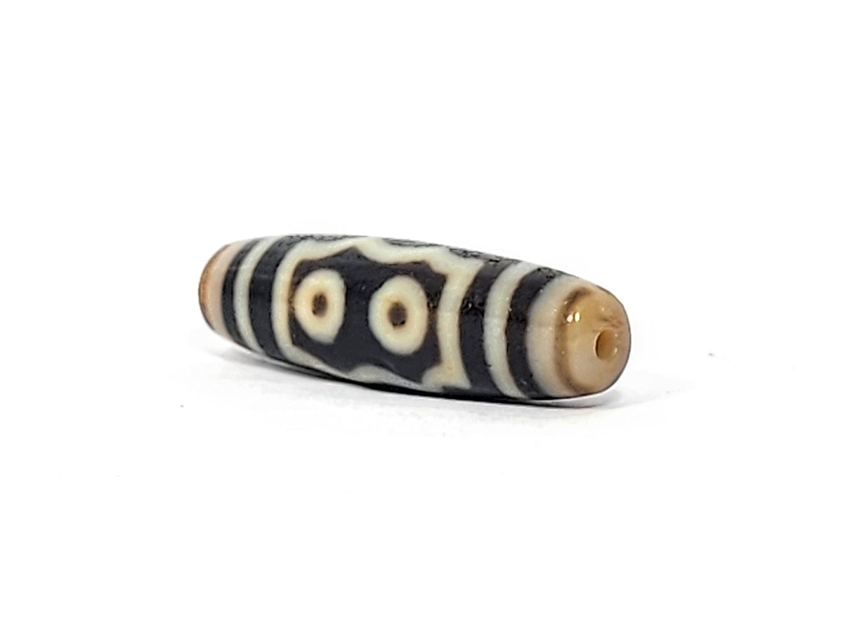 Opposite end cap of antique five eye dzi At-072625-5E, warm honey-tan agate tip with drill hole, two-eye frame face visible, pitch-black body, 44.5mm × 12.4mm, unretouched