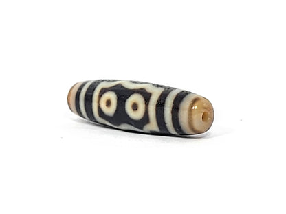 Opposite end cap of antique five eye dzi At-072625-5E, warm honey-tan agate tip with drill hole, two-eye frame face visible, pitch-black body, 44.5mm × 12.4mm, unretouched