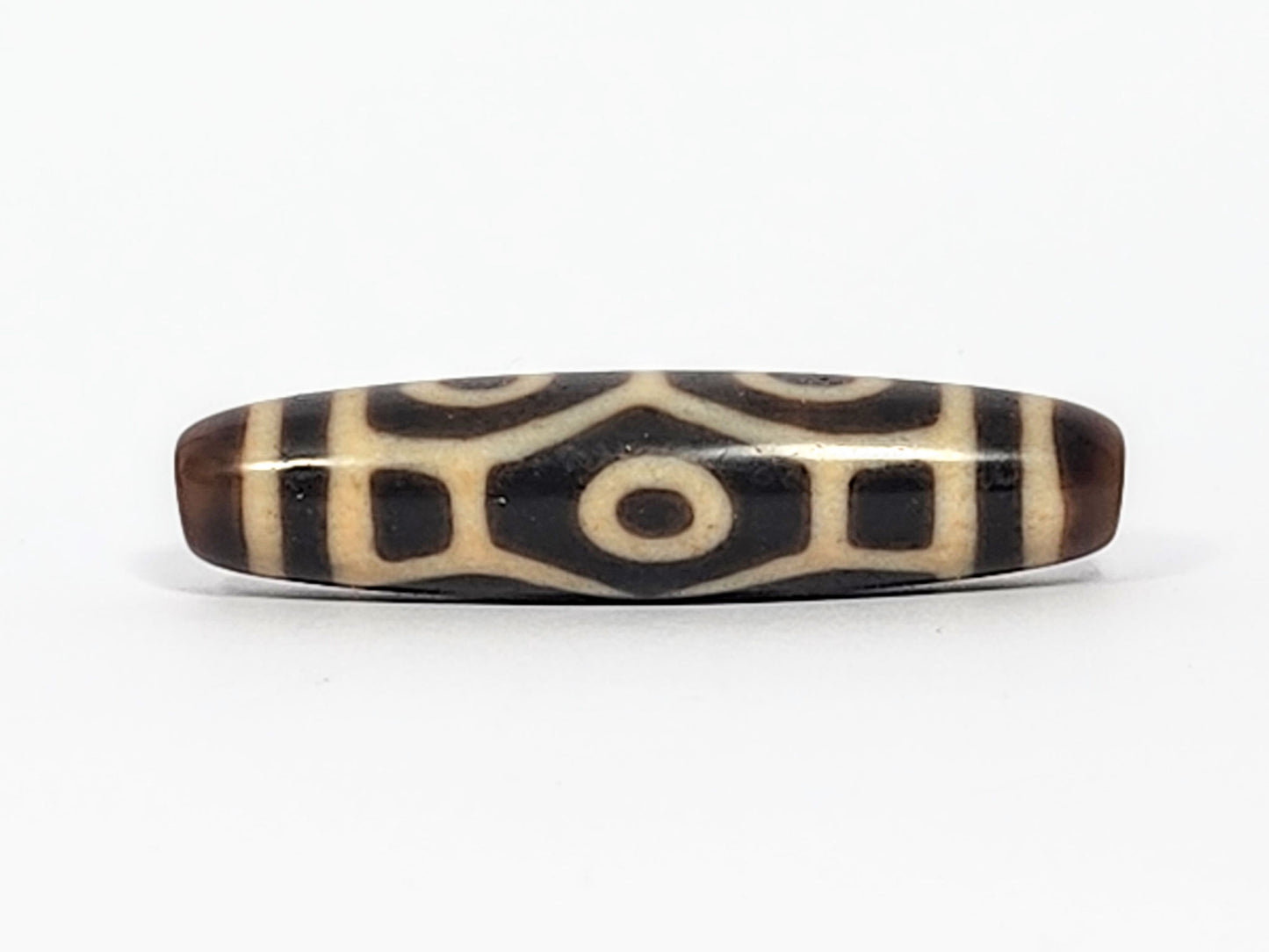Antique Naga dzi bead face B showing architectural body scale with squared dark panels and central eye, At-050725-6EN3