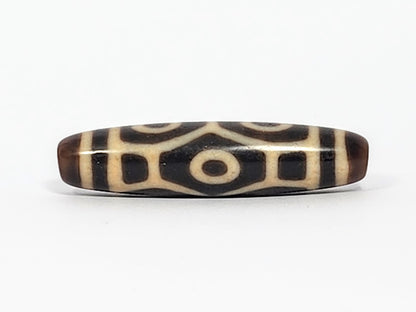Antique Naga dzi bead face B showing architectural body scale with squared dark panels and central eye, At-050725-6EN3
