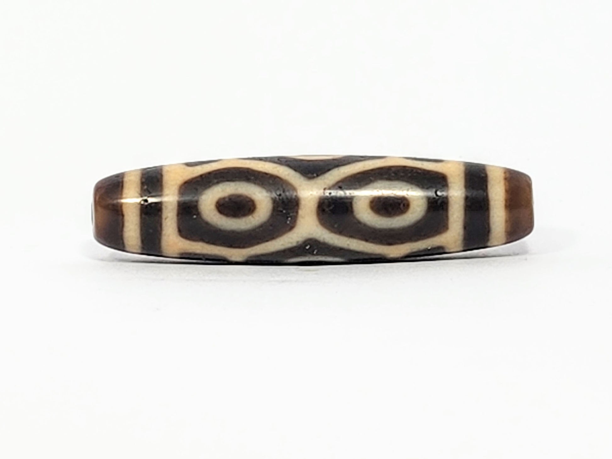 Antique Six Eye Naga dzi bead face C showing paired Dragon eyes with precise cream rings on dark agate, At-050725-6EN3