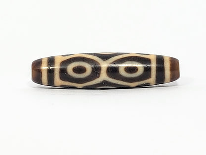 Antique Six Eye Naga dzi bead face C showing paired Dragon eyes with precise cream rings on dark agate, At-050725-6EN3