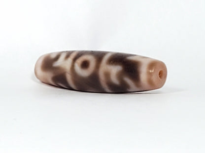 At-060326-GRRP, angled End A, warm cream end cap with drilled hole, paraphernalia motif wrapping body, unretouched