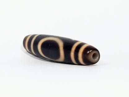Opposite end of antique Tibetan Heaven Earth dzi bead showing drill hole and open arc motif on near-black body, At-082324-HE3