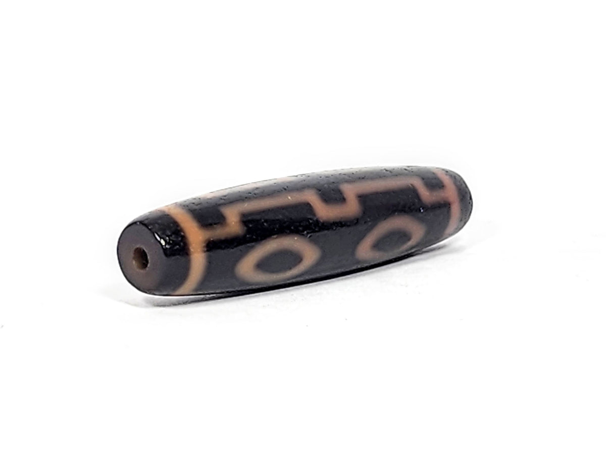 Opposite end cap of antique Four Eye dzi At-012325-4E, deep dark brown agate tip, centred drill hole, amber four eye motif visible on body, unretouched photography