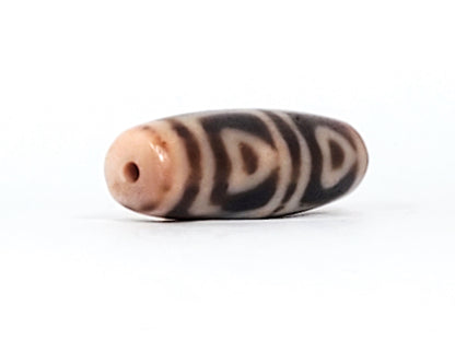 End cap of antique Four Leaf Bodhi dzi bead At-101624-FLB, warm brown agate tip, centred drill hole, compact barrel body, amber ground, unretouched photography