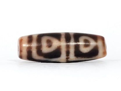 Antique Tibetan Four Leaf Bodhi dzi bead At-101624-FLB, front face showing four arch-leaf motifs in cream on amber-brown agate, bloodspots visible, 35.7mm × 12.1mm, unretouched