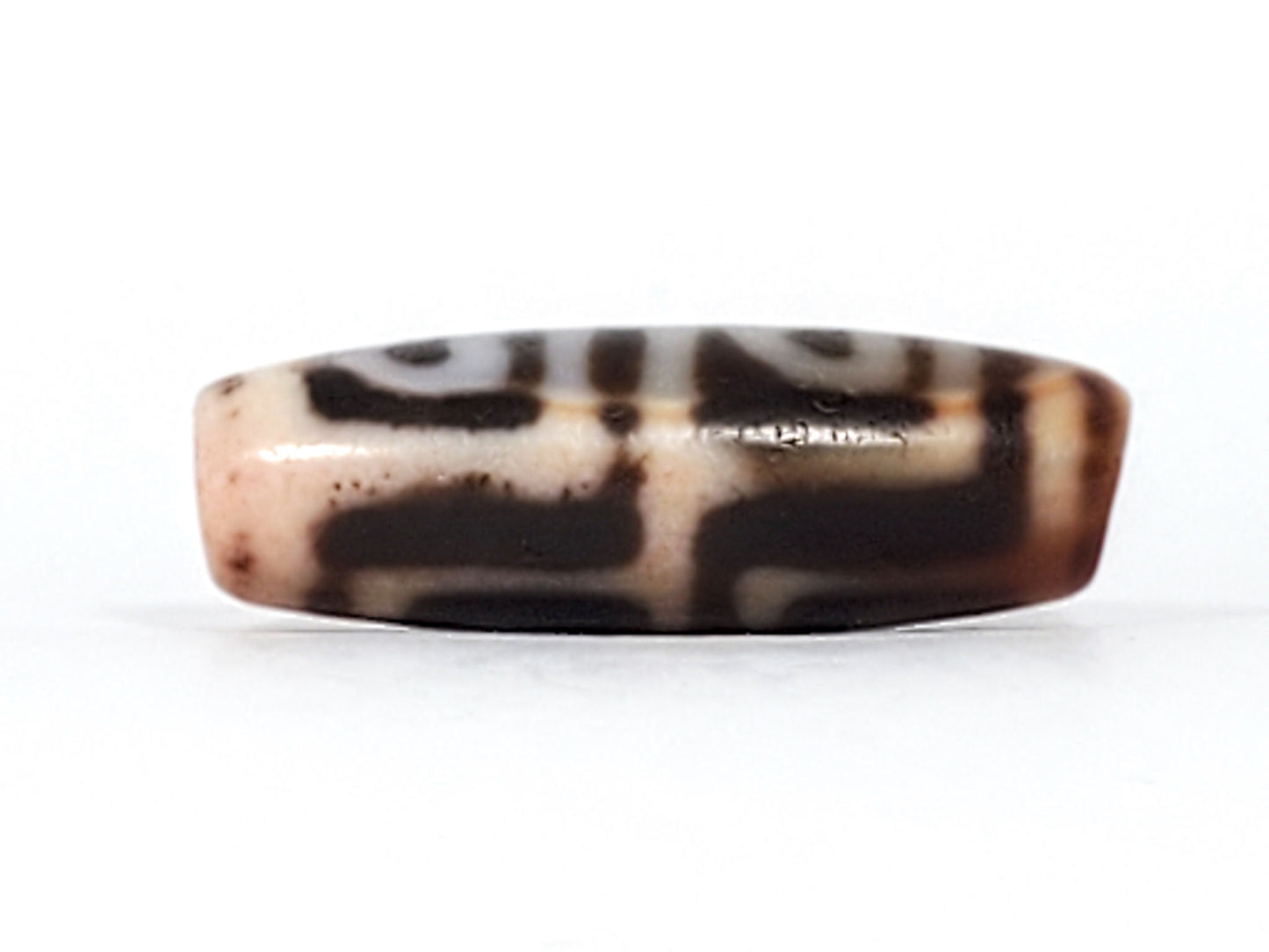 Three-quarter view of antique Four Leaf Bodhi dzi bead At-101624-FLB, compact barrel body, warm amber-brown agate, four arch-leaf motif, natural weathering marks, unretouched
