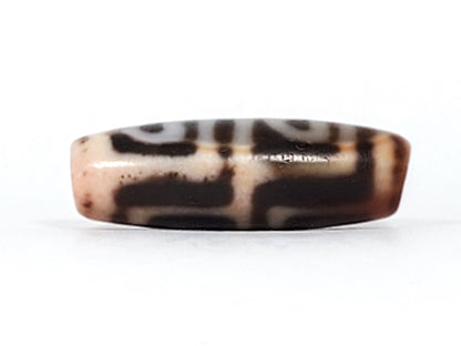 Three-quarter view of antique Four Leaf Bodhi dzi bead At-101624-FLB, compact barrel body, warm amber-brown agate, four arch-leaf motif, natural weathering marks, unretouched