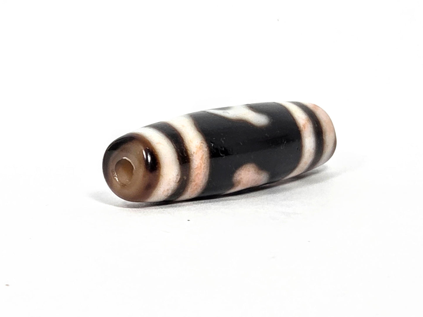 At-080426-GTBS antique Green Tara dzi bead 37.9×11.0mm, opposite drill-end angled view showing cream-brown agate end cap, cylindrical barrel form, unretouched