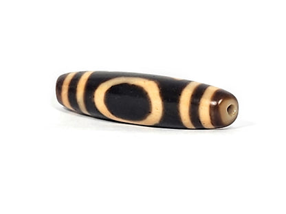 Angled end view of antique Heaven Earth dzi bead showing oval motif and drill hole in warm brown agate cap, At-121824-HE2