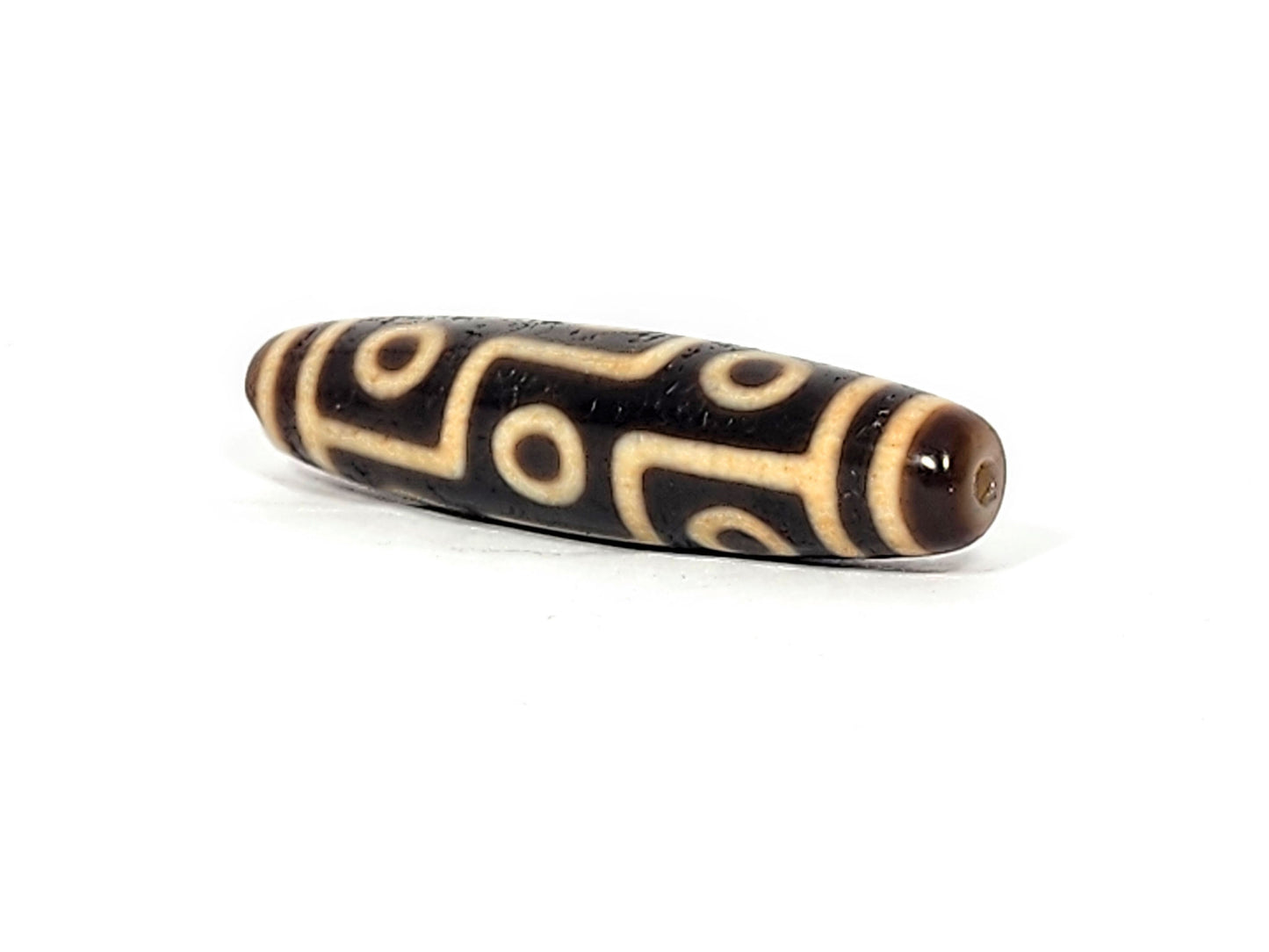 Opposite end of antique Tibetan Nine Eye dzi bead showing drill hole and connected eye motif on brown agate, At-011625-9E