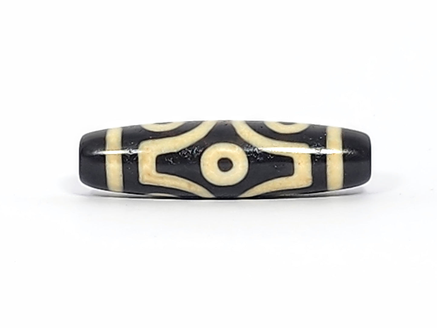 Face D of antique six eye dzi At-042925-6E2, single eye in diamond compass-rose frame, pitch-black agate, four concave-pointed extensions, bright cream, unretouched photography