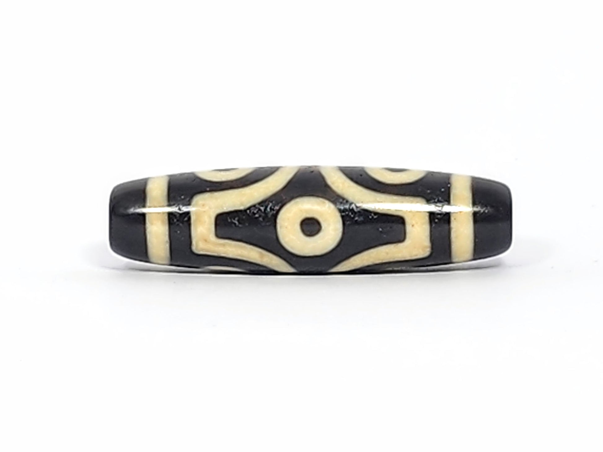 Face D of antique six eye dzi At-042925-6E2, single eye in diamond compass-rose frame, pitch-black agate, four concave-pointed extensions, bright cream, unretouched photography
