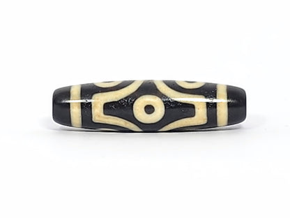Face D of antique six eye dzi At-042925-6E2, single eye in diamond compass-rose frame, pitch-black agate, four concave-pointed extensions, bright cream, unretouched photography