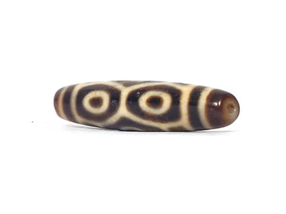 Angled end view of antique Naga Dragon Eye dzi bead showing paired eyes and drill hole in dark brown cap, At-092524-6EN