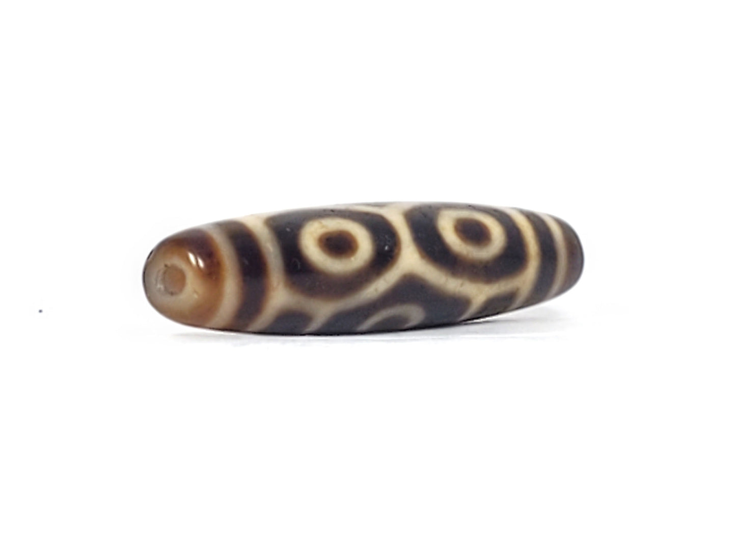 Opposite end of antique Tibetan Naga Dragon Eye dzi bead showing drill hole and paired eye motif, At-092524-6EN