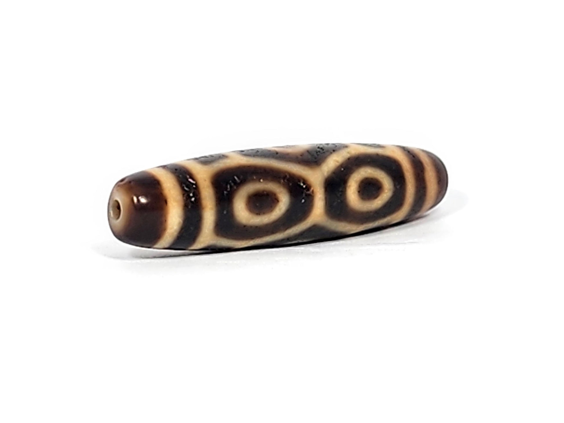 Opposite end of antique Six Eye Naga dzi bead showing drill hole in brown cap and paired eye motif, At-122124-6EN2