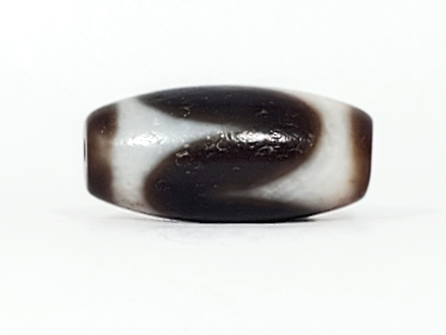 Third face of antique Tasso dzi At-093024-TaBS3, sweeping cream wave motif on chocolate-brown agate, bloodspot cinnabar inclusions visible, wide disc-like barrel form, unretouched