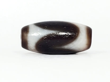 Third face of antique Tasso dzi At-093024-TaBS3, sweeping cream wave motif on chocolate-brown agate, bloodspot cinnabar inclusions visible, wide disc-like barrel form, unretouched