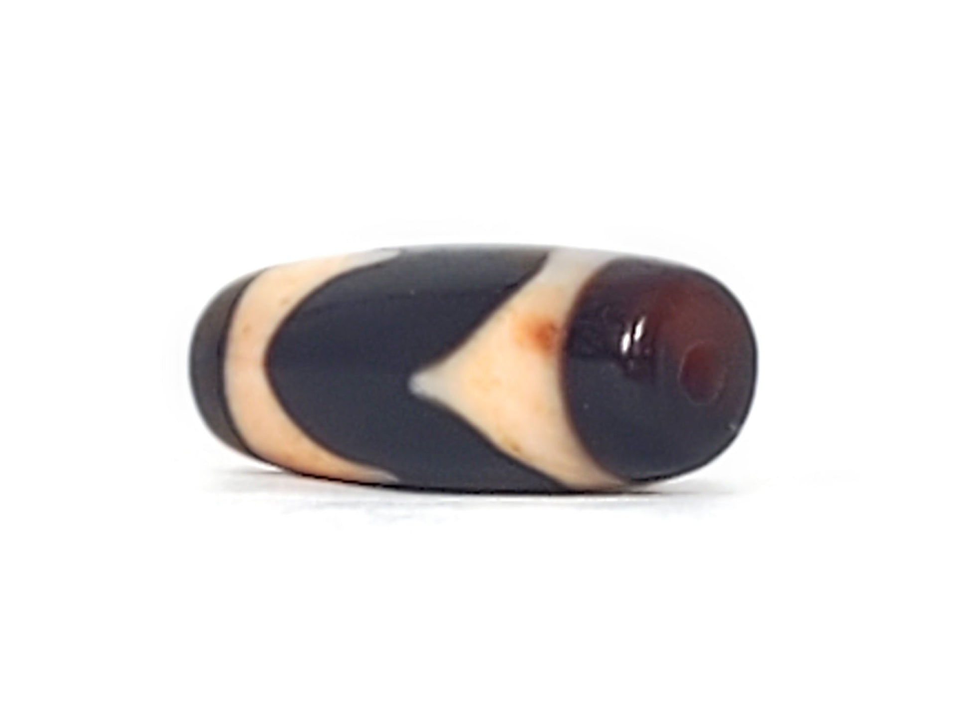 Opposite end cap of antique Tasso dzi At-092924-TaBS2, pitch-black agate tip, drill hole centred, cream Tasso zones with bloodspot inclusions visible, 28.7mm × 11.2mm