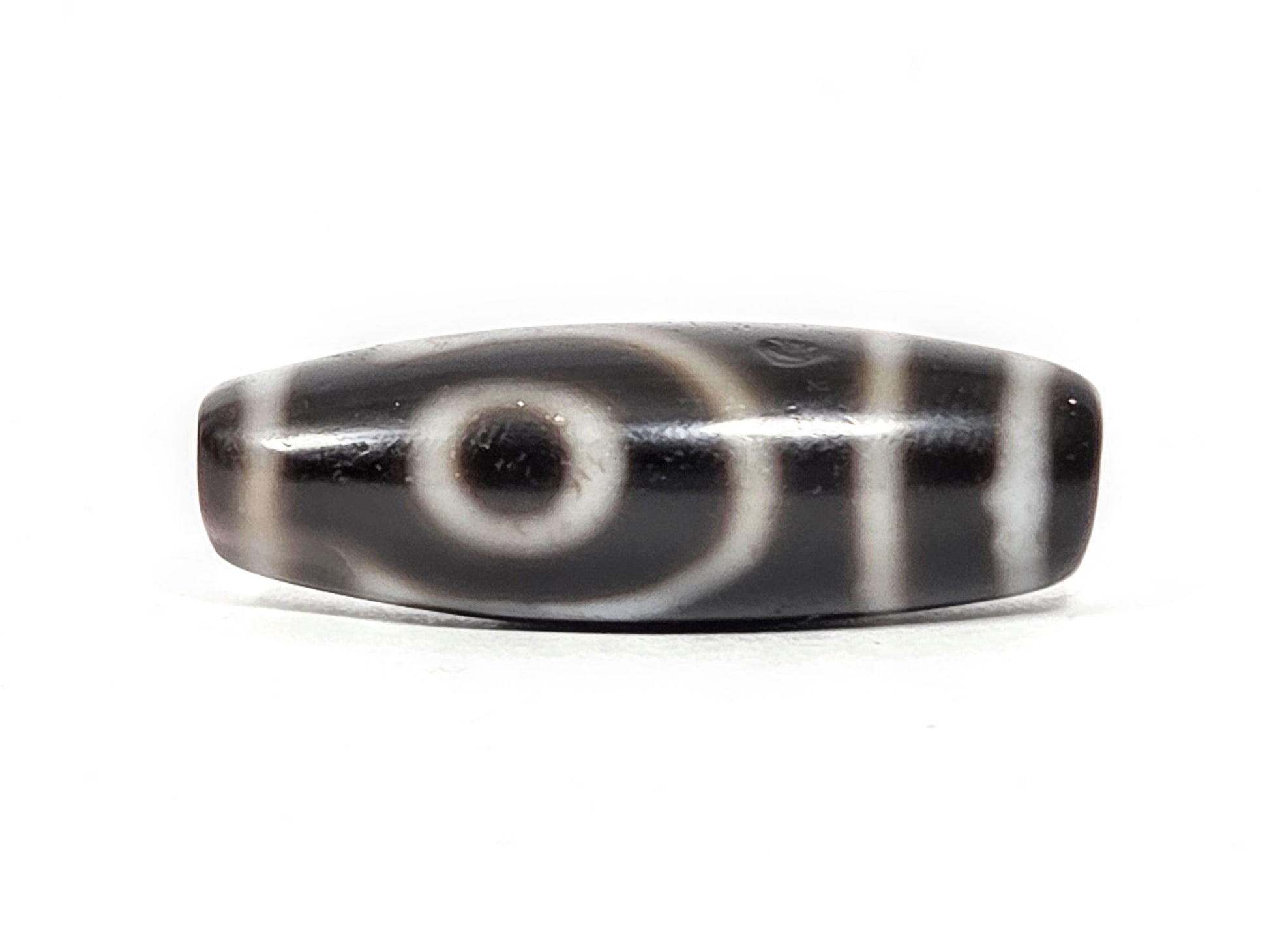 Antique two eye dzi At-033126-2E4, Face A, fully closed concentric-ring eye on pitch-black agate, vertical cream stripes right, 37.3mm × 12.8mm, unretouched photography