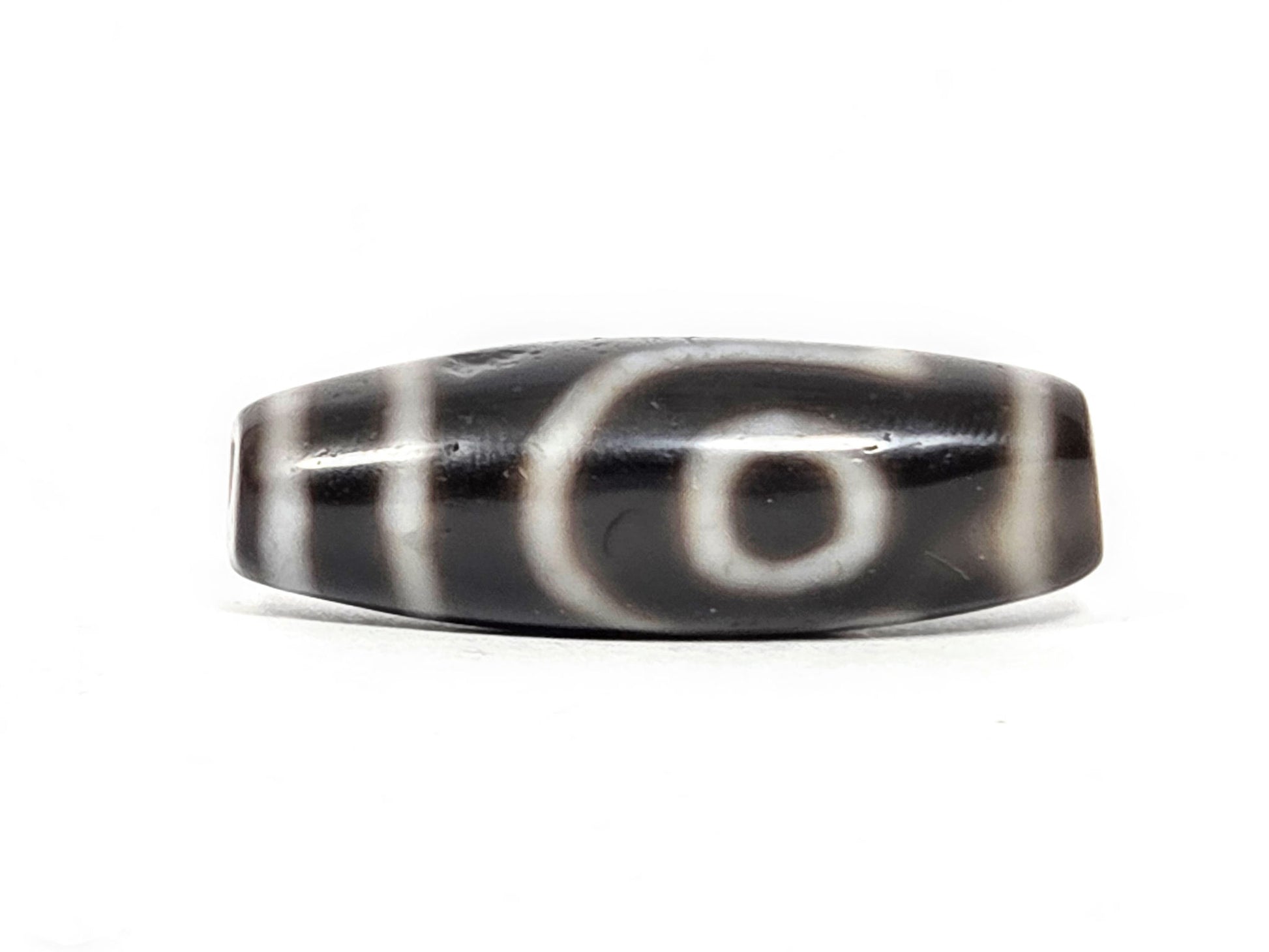 Face B of antique two eye dzi At-033126-2E4, open C-ring eye on pitch-black agate, incomplete outer arc, vertical cream stripes, 37.3mm × 12.8mm, unretouched photography