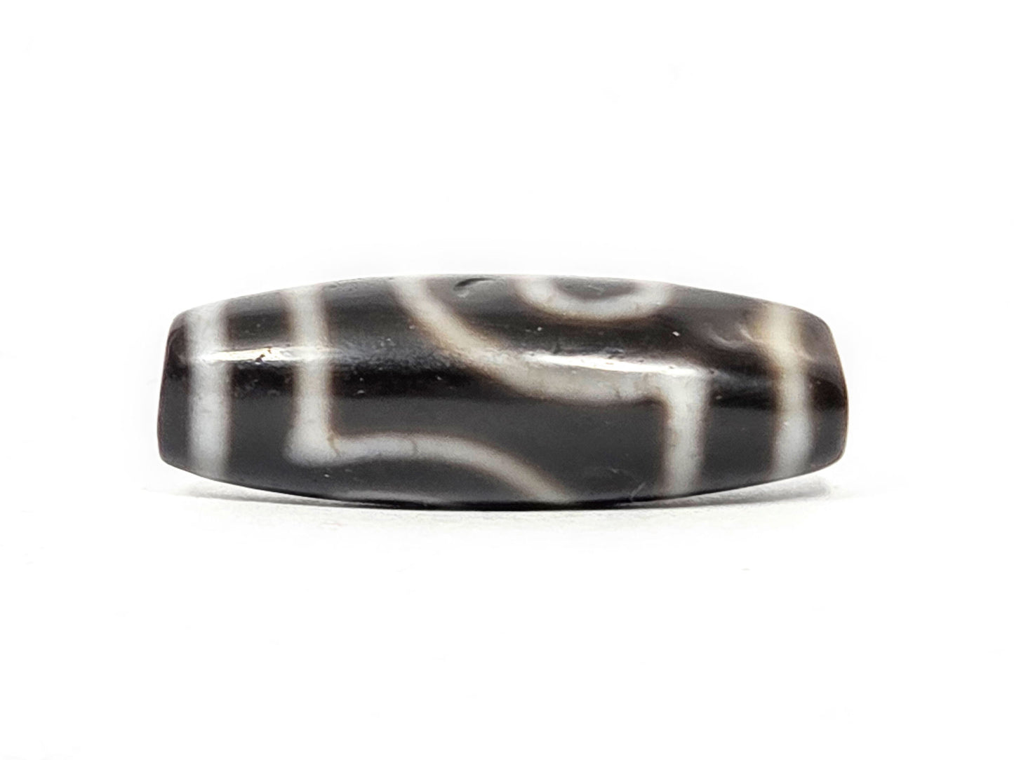 Alternate angle of antique two eye dzi At-033126-2E4, cream scroll wave motif on pitch-black agate, medicine dig face from different rotation, 37.3mm, unretouched