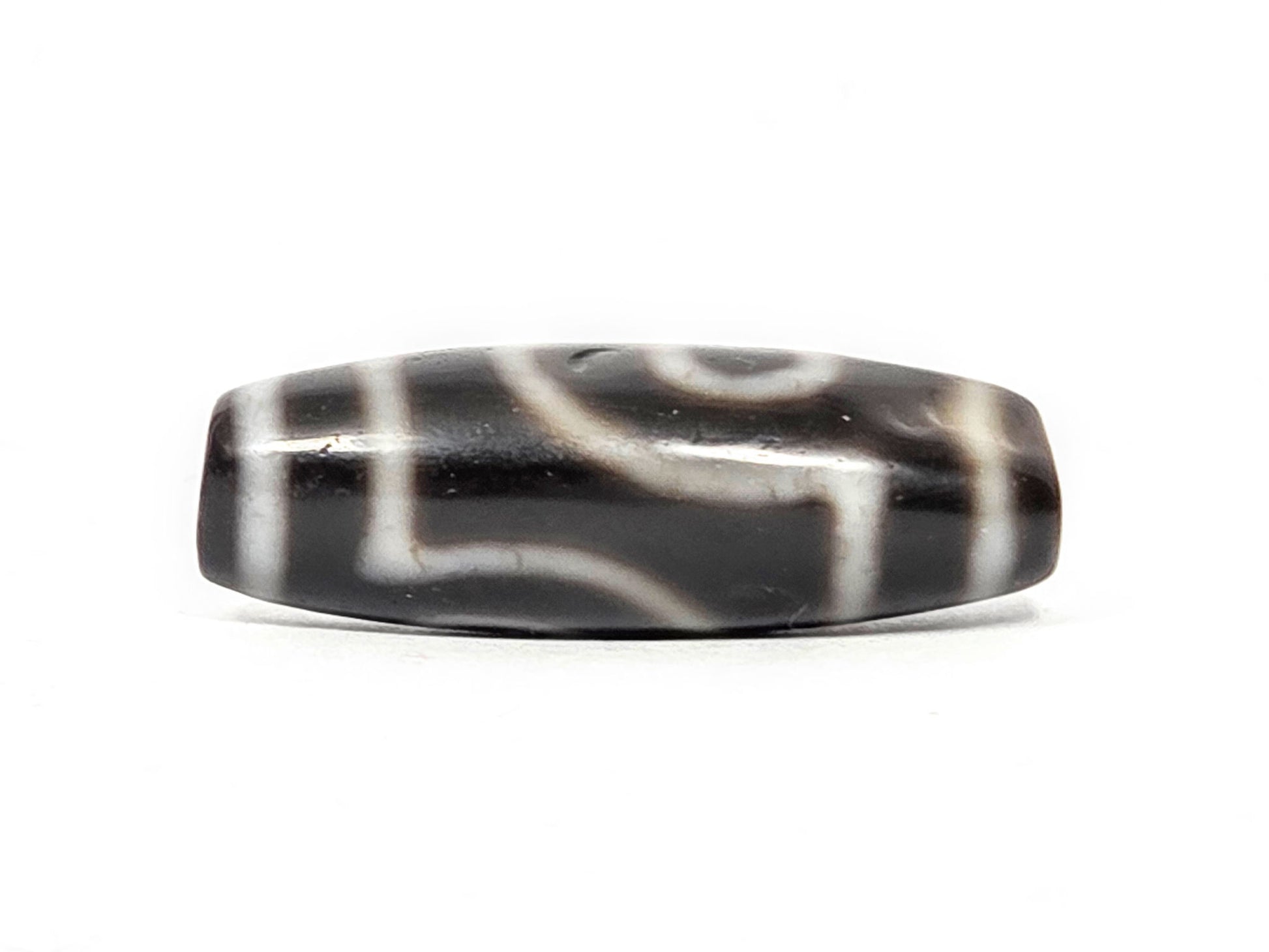 Alternate angle of antique two eye dzi At-033126-2E4, cream scroll wave motif on pitch-black agate, medicine dig face from different rotation, 37.3mm, unretouched