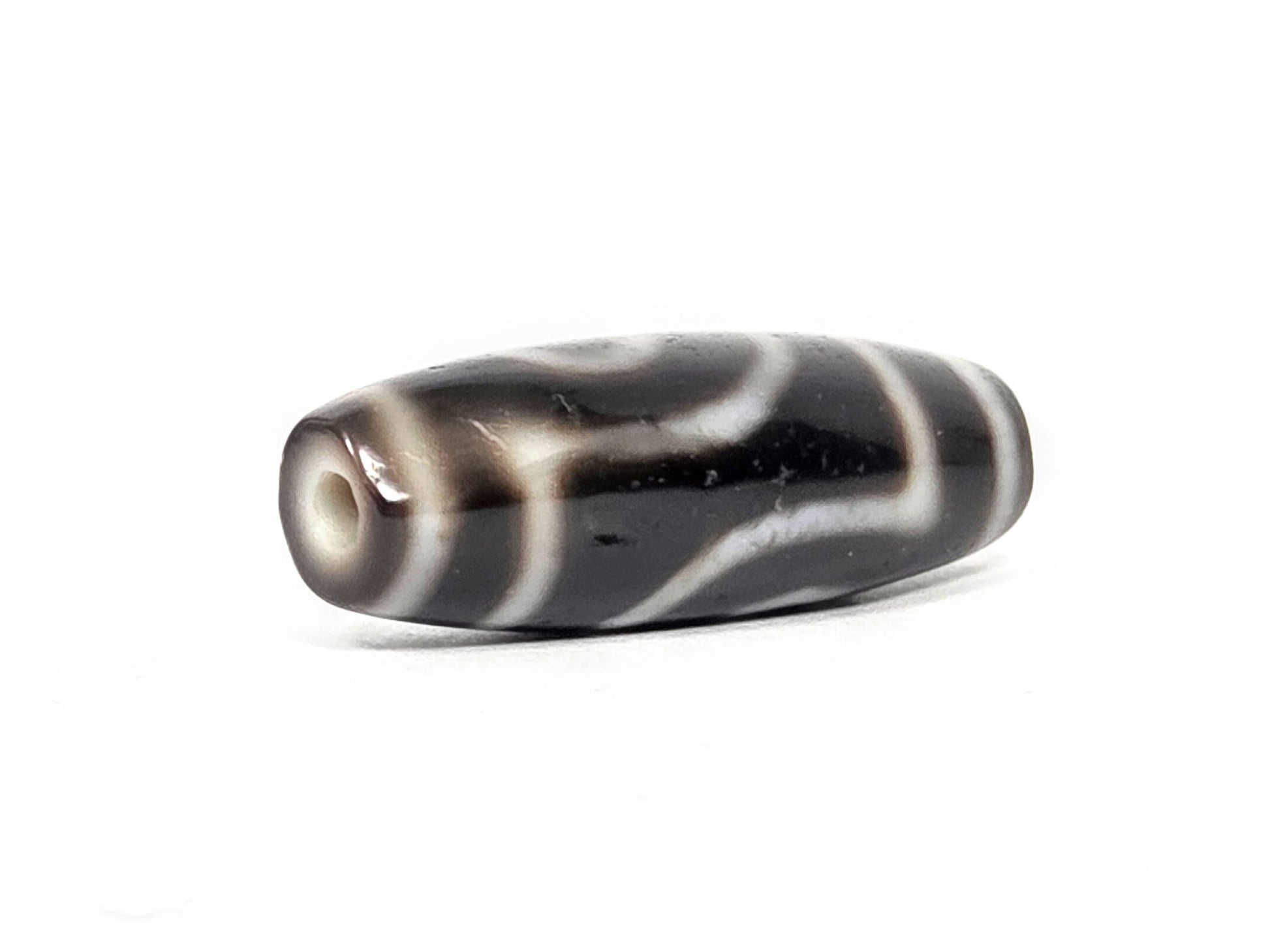 Opposite end cap of antique two eye dzi At-033126-2E4, pitch-black agate tip, cream-ringed drill hole, torpedo body profile, pitch-black throughout, 37.3mm, unretouched