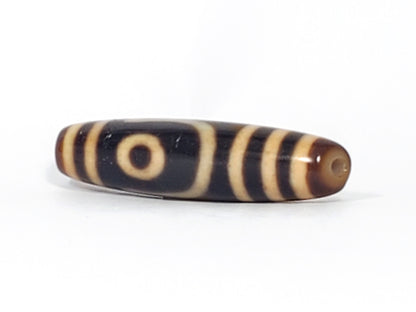 Angled end view of antique Two Eye dzi bead showing single eye and drill hole in warm brown end cap, At-082624-2E