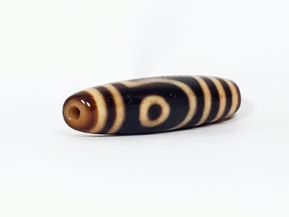 Opposite end of antique Tibetan Two Eye dzi bead showing drill hole in warm brown cap and eye motif, At-082624-2E