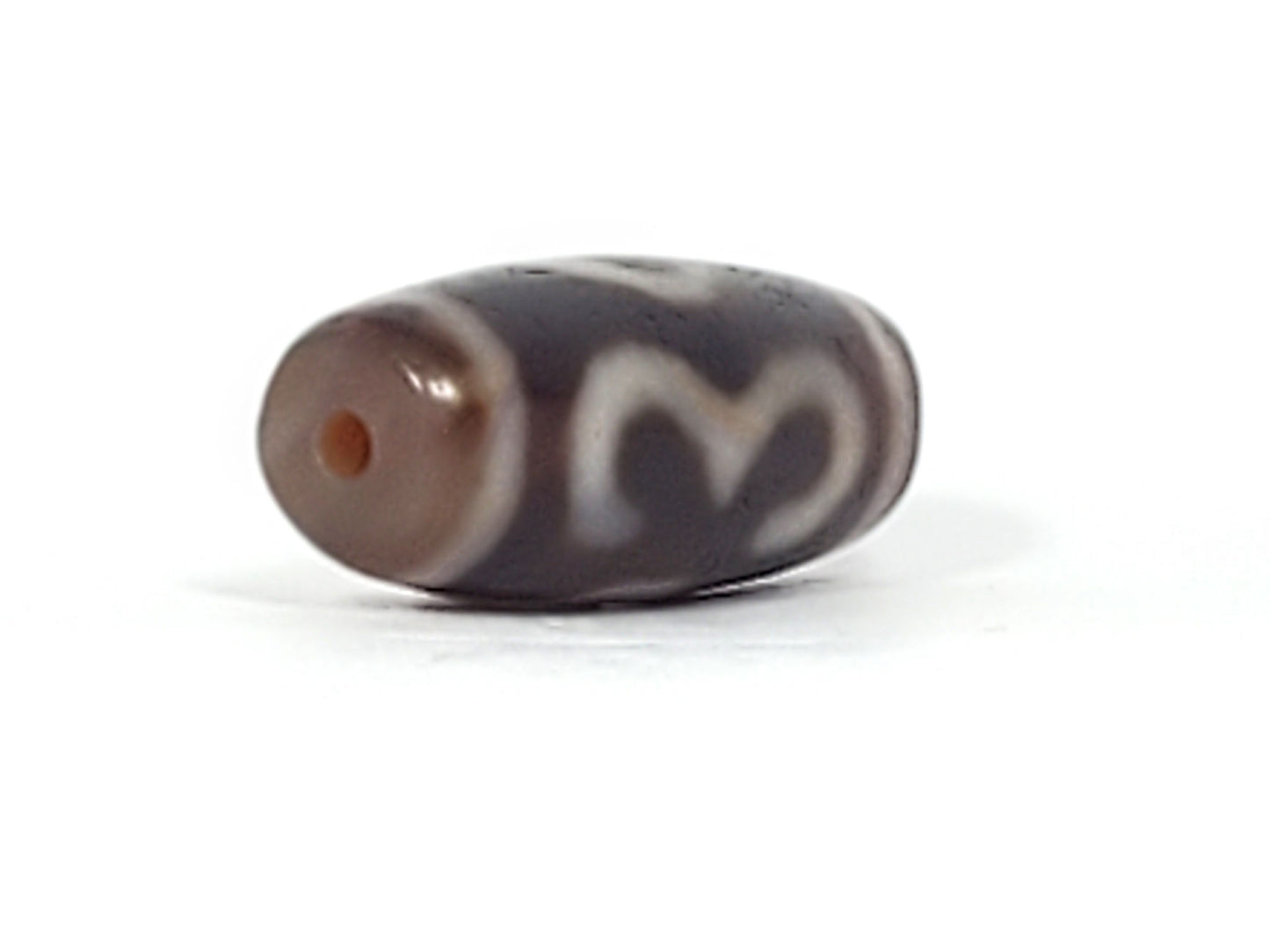 Opposite end detail of antique Double Bat Two Eye dzi At-053026-DB2E, dark brown agate, drill hole, bat and two-eye motif wrapping body, natural weathering marks, unretouched