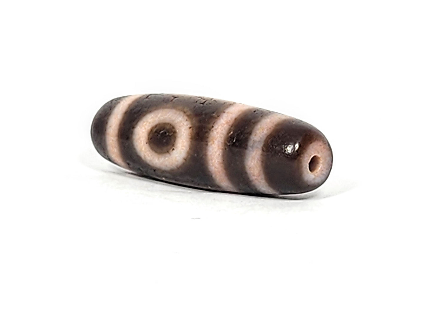 Opposite end cap of antique two eye dzi At-092724-2EBS, cream-ringed drill hole, both eyes visible simultaneously, dark brown agate torpedo, extreme bloodspot saturation, unretouched