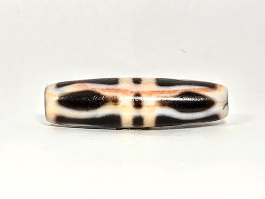 At-070626-3VjBS hero flat, triple vajra dzi, 42.8×12.1mm, cream-dominant ground, dark brown motif arms, unretouched