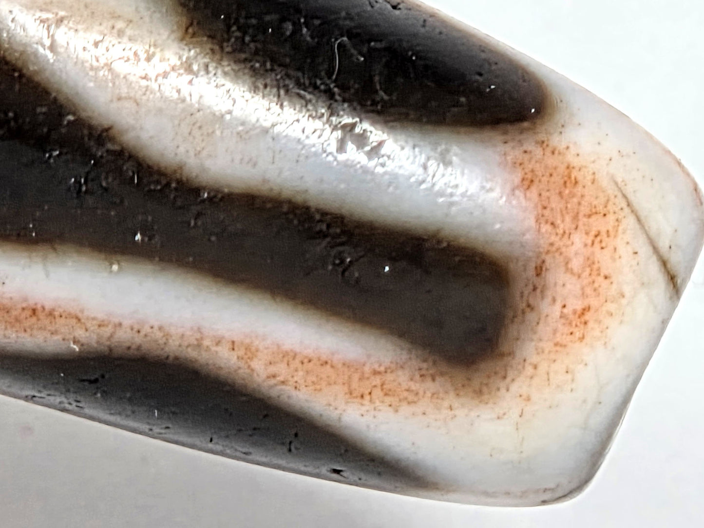 At-070626-3VjBS macro shoulder zone, fine hairline visible, warm terracotta cinnabar diffusion, unretouched