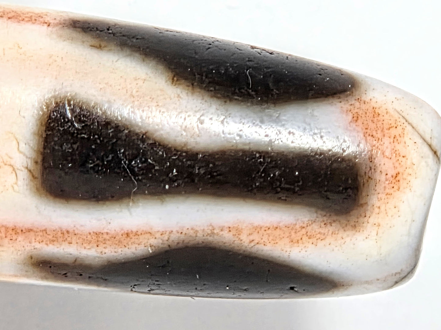 At-070626-3VjBS macro drill-end shoulder, edge wear disclosed, fine hairline, warm cinnabar saturation, unretouched