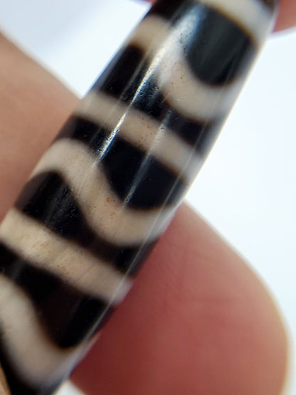 Close-up of antique Wave Stripe dzi held in hand showing crisp black-white banding and wave motif, At-052526-WS
