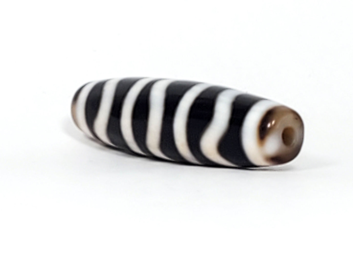 End view of antique Wave Stripe dzi bead showing drill hole with brown agate bloodspot surround, At-052526-WS