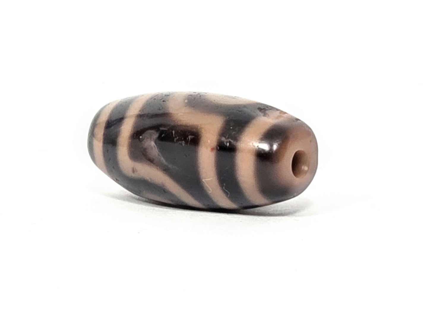 At-033126-2E5, sandy-cream end cap with drilled hole, angled view, dark-brown body, unretouched photo