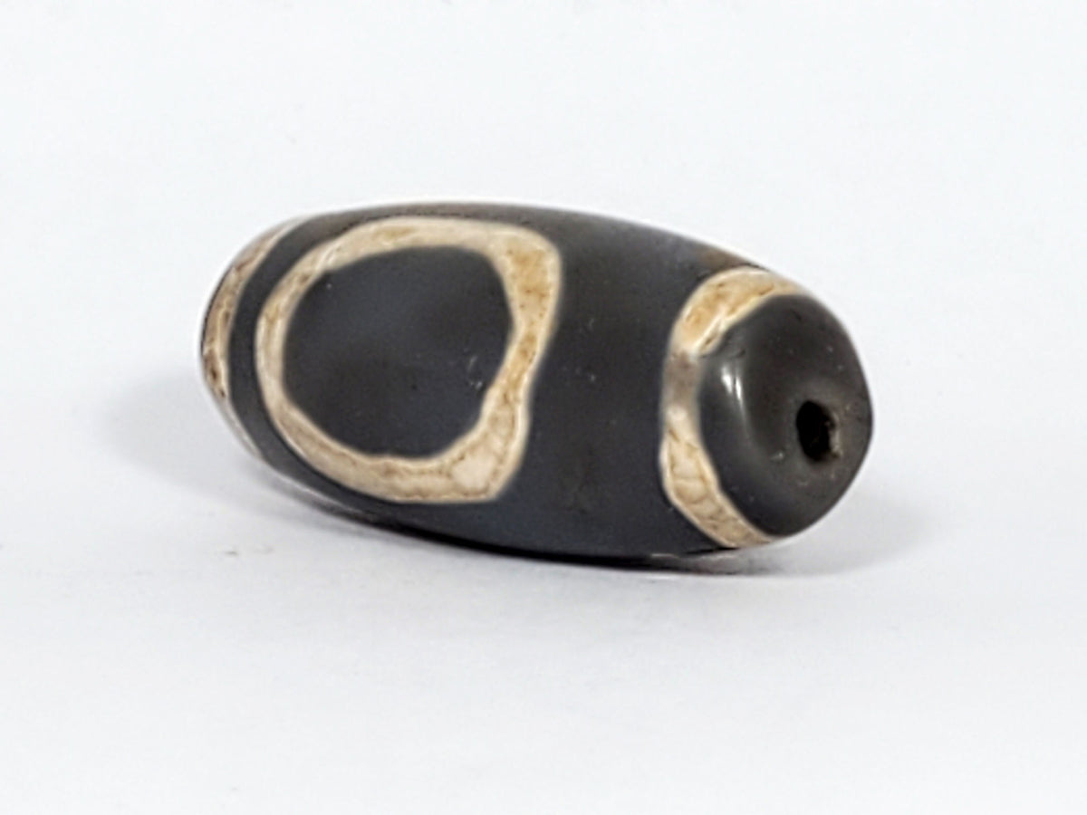 At-022624-HEG, angled End B, glassy charcoal-grey end cap and drilled hole, open oval gate wrapping body, unretouched