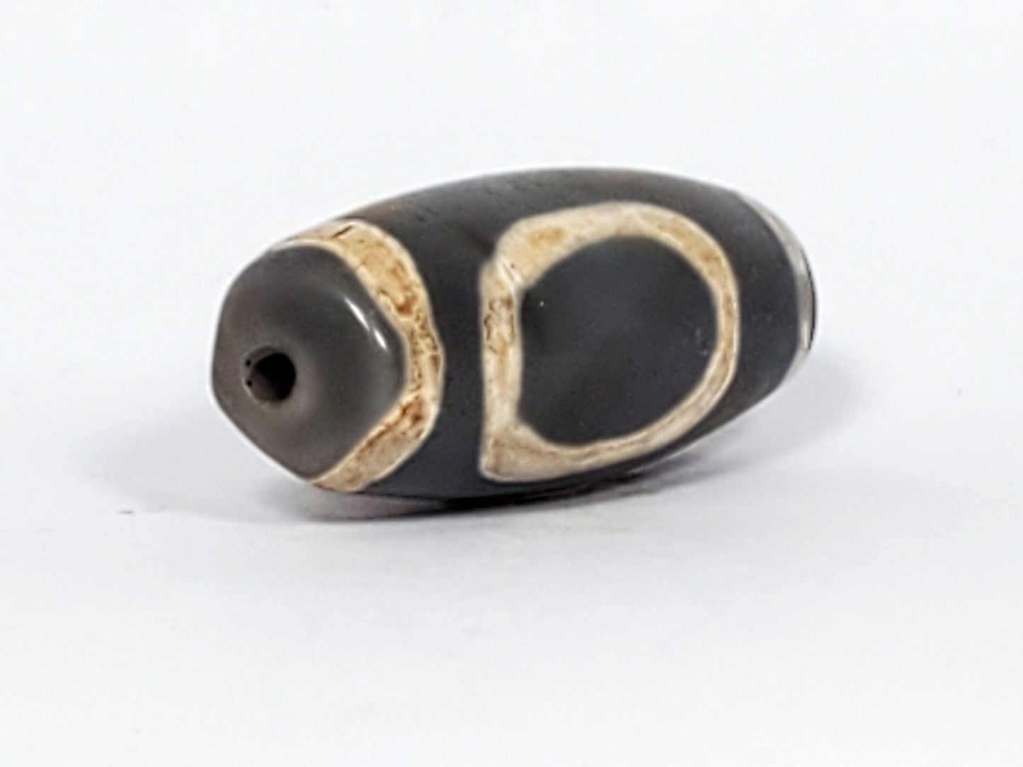 At-022624-HEG, angled End A, charcoal-grey end cap with drilled hole, open oval gate sweeping body, unretouched