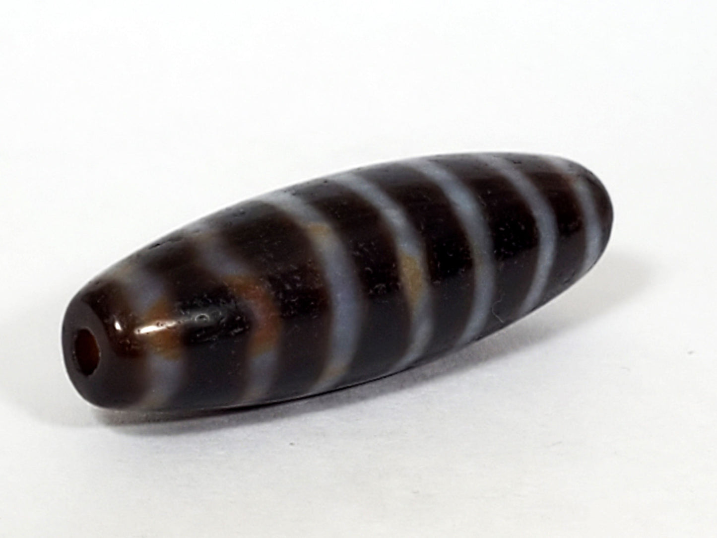 At-053126-WS2, angled end-cap view, drilled hole, stripe bands wrap spindle form, chocolate-brown agate, unretouched