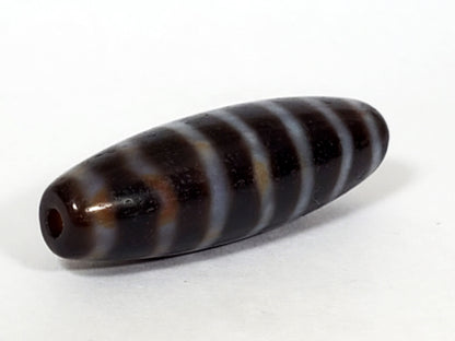 At-053126-WS2, angled end-cap view, drilled hole, stripe bands wrap spindle form, chocolate-brown agate, unretouched