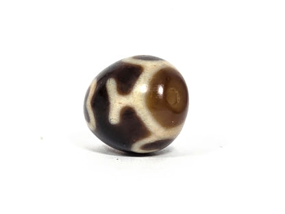 At-080926-4ELT antique round dzi bead 19.9×16.6mm, rotation F showing cream heart-lotus form and drill hole at lower left, unretouched