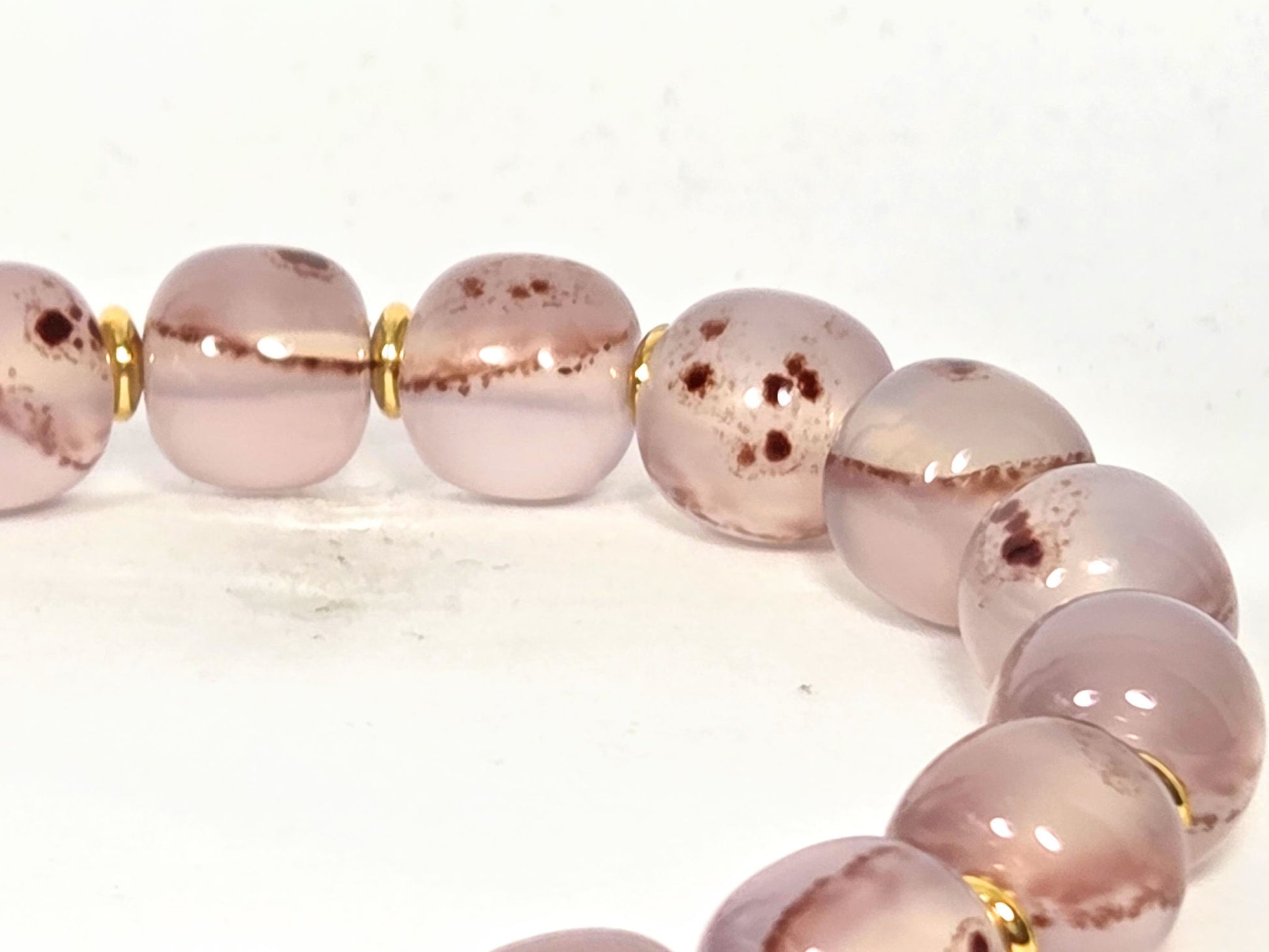 N-030526-CB2 arc detail, pale lavender-blush translucent chalcedony, rust-brown banding, gold spacers, unretouched