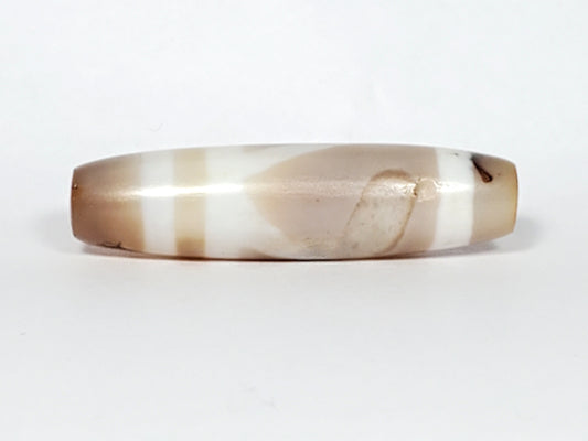 Ancient double mountain motif dzi bead, banded agate, cream and tan striping, elongated barrel shape, visible drill hole, natural patina