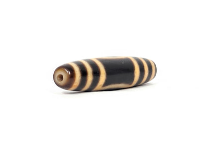 Antique heaven earth dzi — angled end, drill hole at warm brown rounded tip, amber stripe rings on black body, At-0426-HE